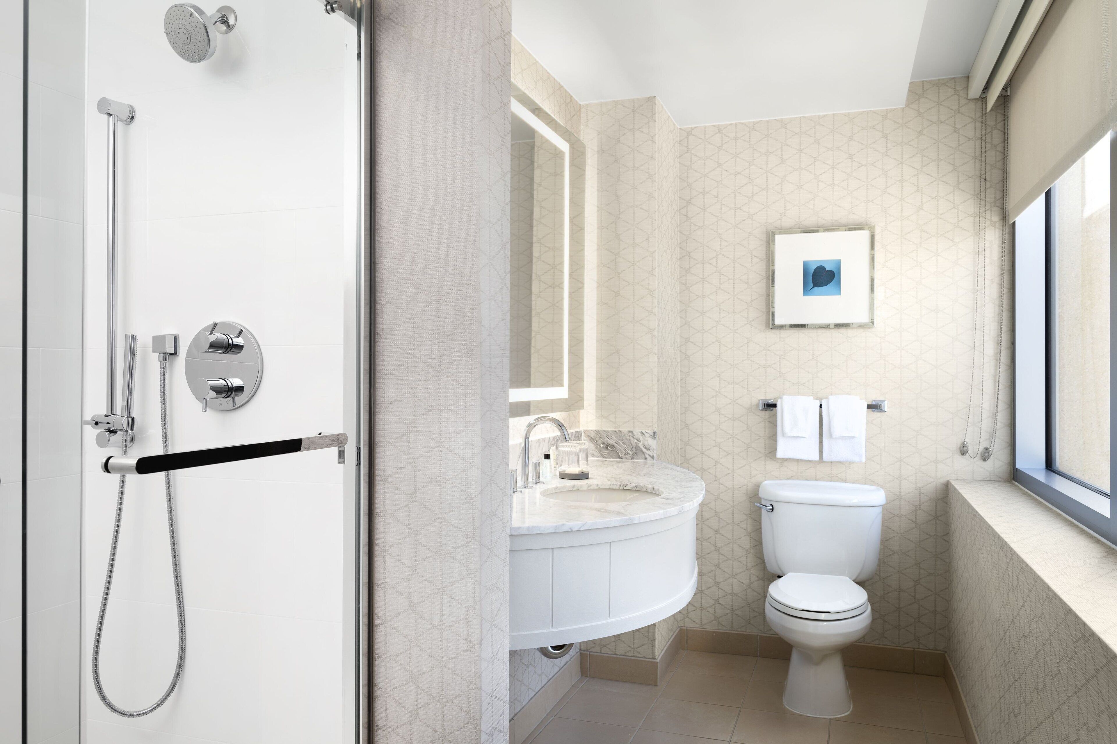 A modern bathroom with a shower, toilet, and sink.