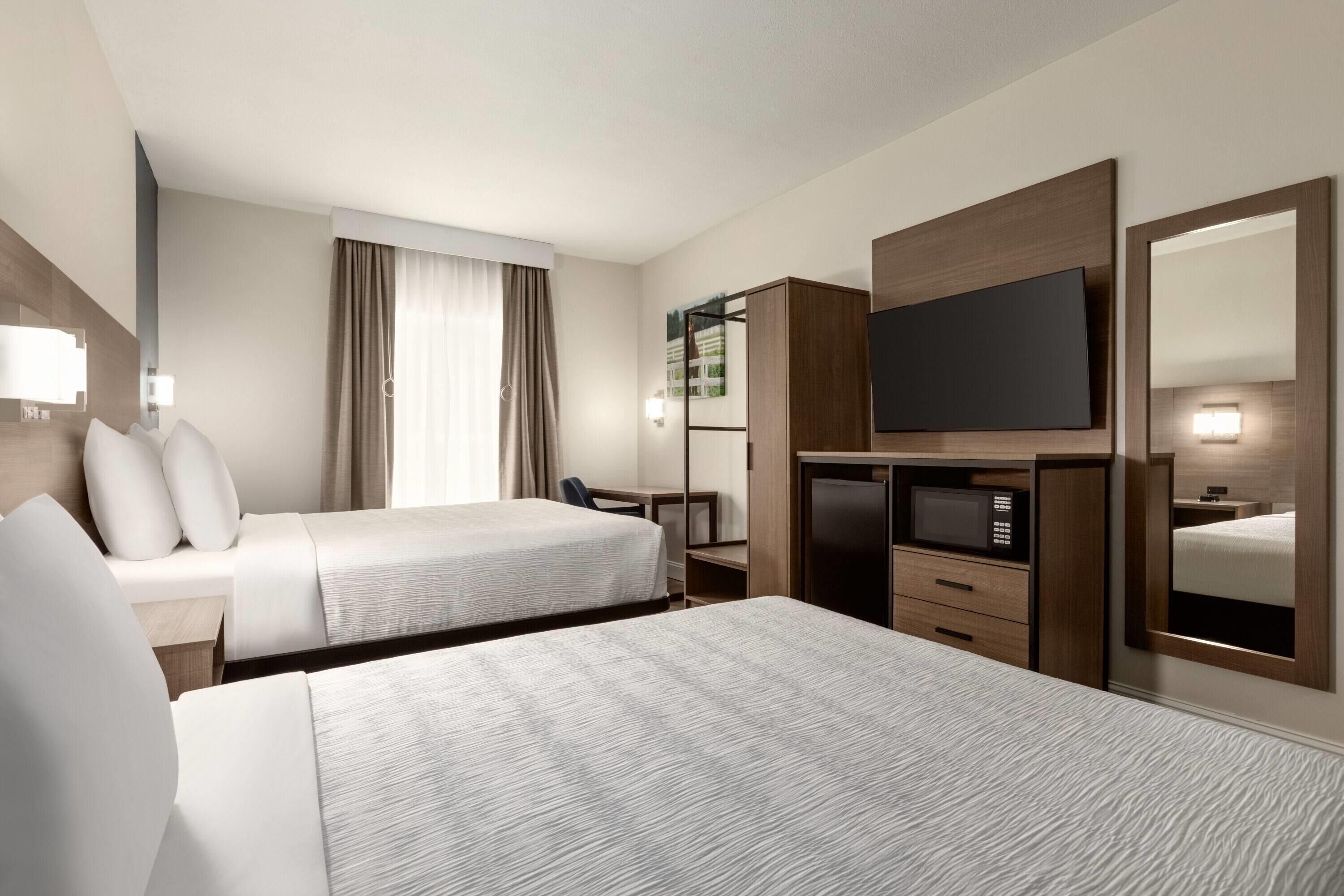A hotel room with two beds, a TV, a desk, and a wardrobe.
