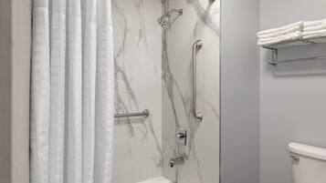 Un baño con bañera, ducha con puerta de vidrio y un perchero para toallas.