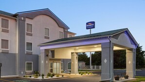 Un hotel con entrada cubierta, un cartel que indica que pertenece a Wyndham y un estacionamiento con espacios delimitados.