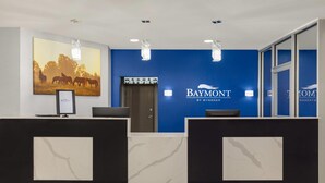 A reception area with a blue wall, a mounted painting of horses, and a Baymont logo.