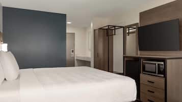 Una habitación de hotel con cama, armario, televisión y microondas.