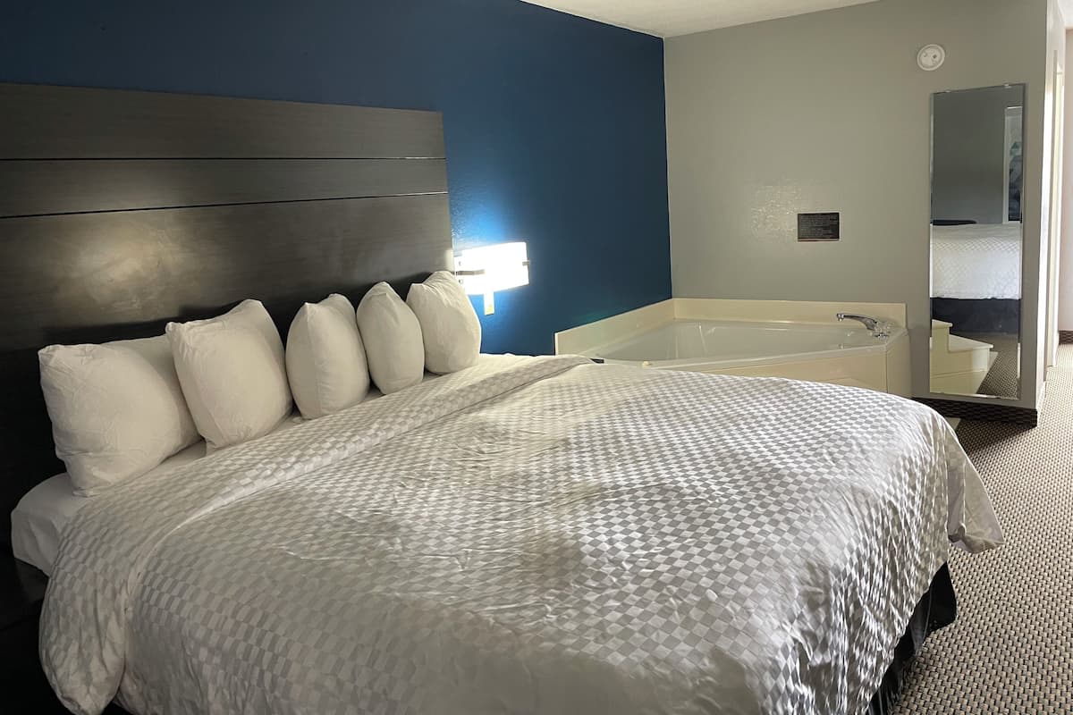 Hotellihuone, jossa on suuri sänky, erillinen kylpyhuone, jossa on kylpyamme, sekä peili.