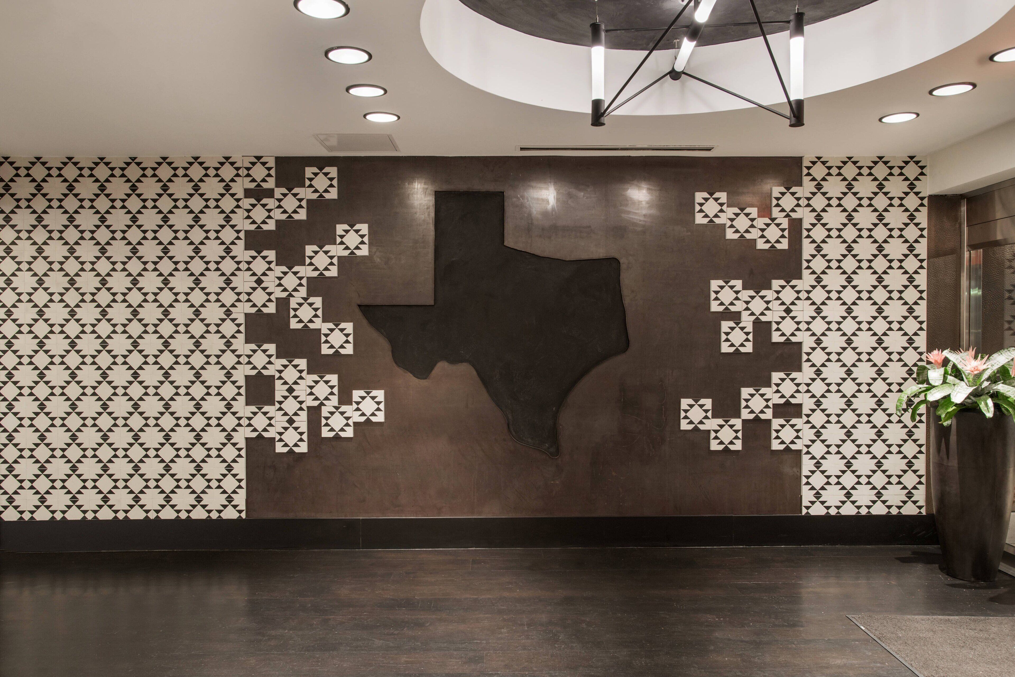 Een hal met een geometrisch wandontwerp, een grote silhouet van Texas en een potplant.