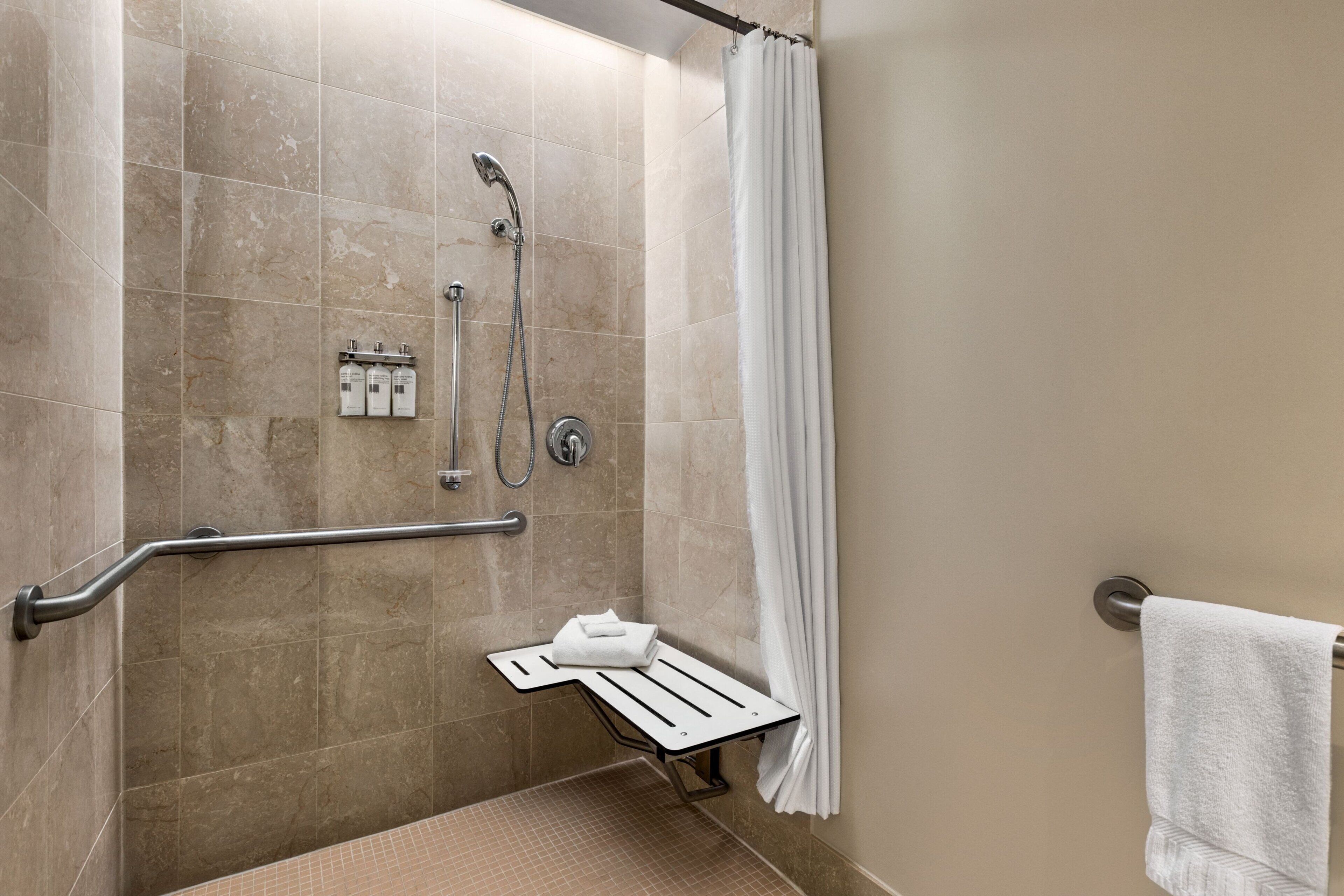 A shower area with a grab bar, a towel rack, and a showerhead.