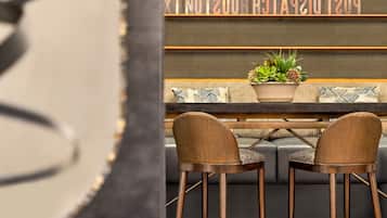 Un espace d’accueil moderne comprenant un canapé, deux fauteuils, une plante en pot et un panneau indiquant la mention « POSTMASTER ».