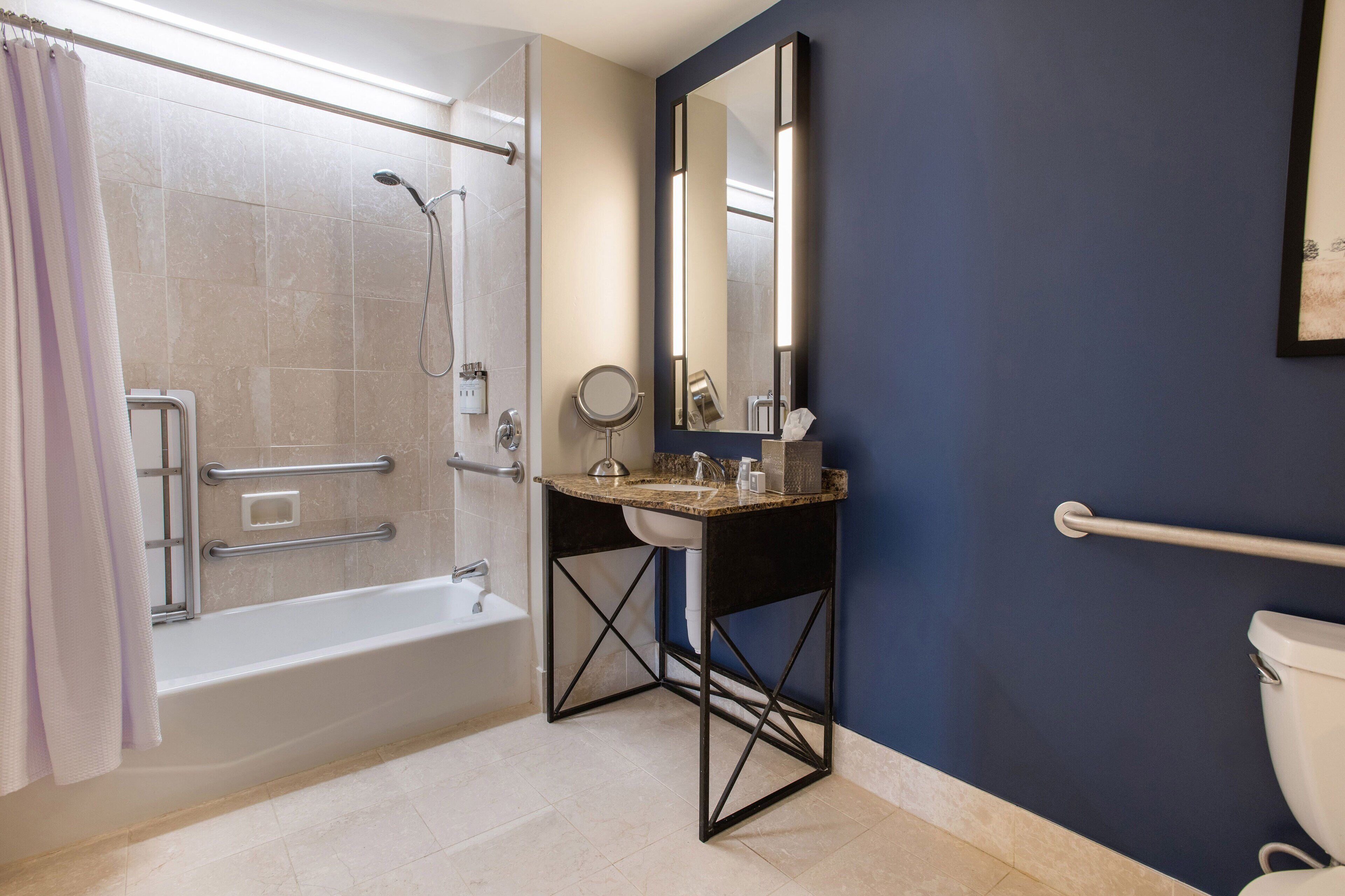 A bathroom with a bathtub, a sink with a mirror, and a toilet.