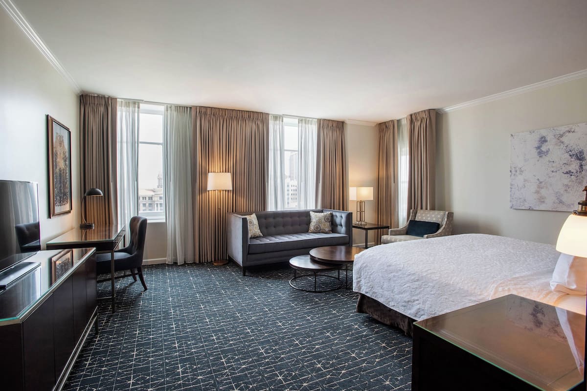 Ein Hotelzimmer mit Bett, einer Couch, einem Schreibtisch und einem Sessel.
