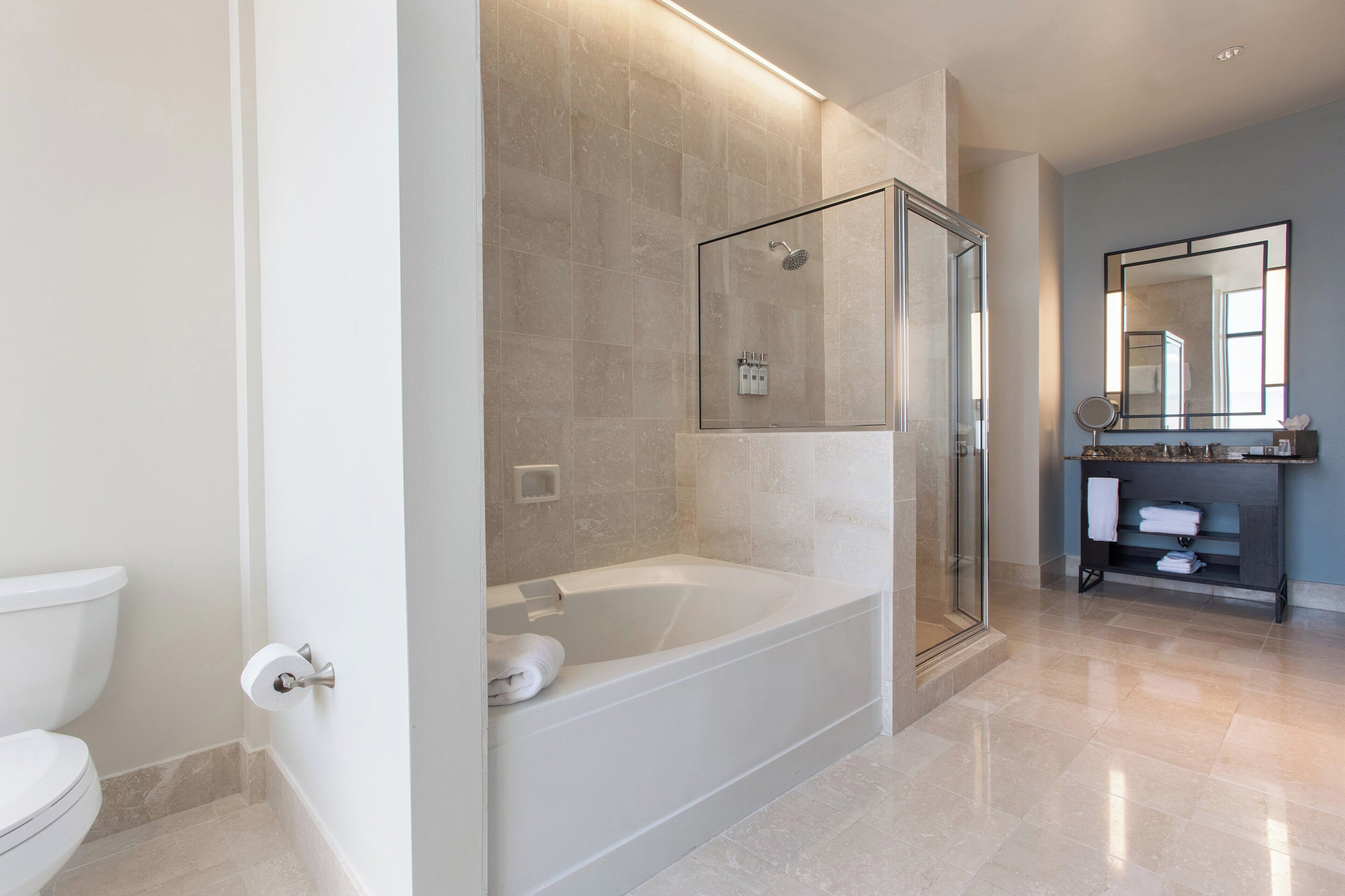 A modern bathroom with a glass-enclosed shower, a freestanding bathtub, and a vanity with a mirror.