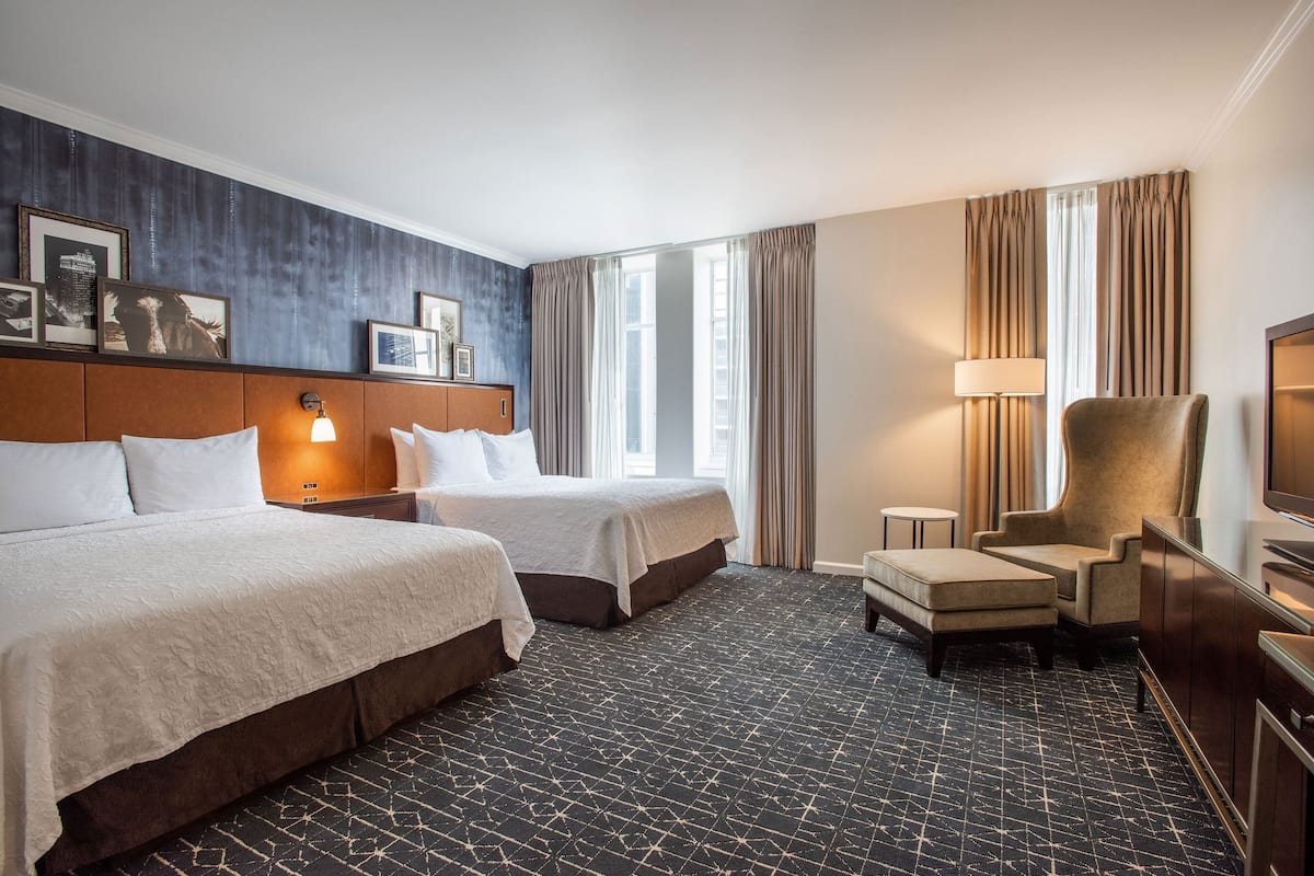 Ein Hotelzimmer mit zwei Betten, einem Schlafsofa, einem Fernseher und einem Schreibtisch.