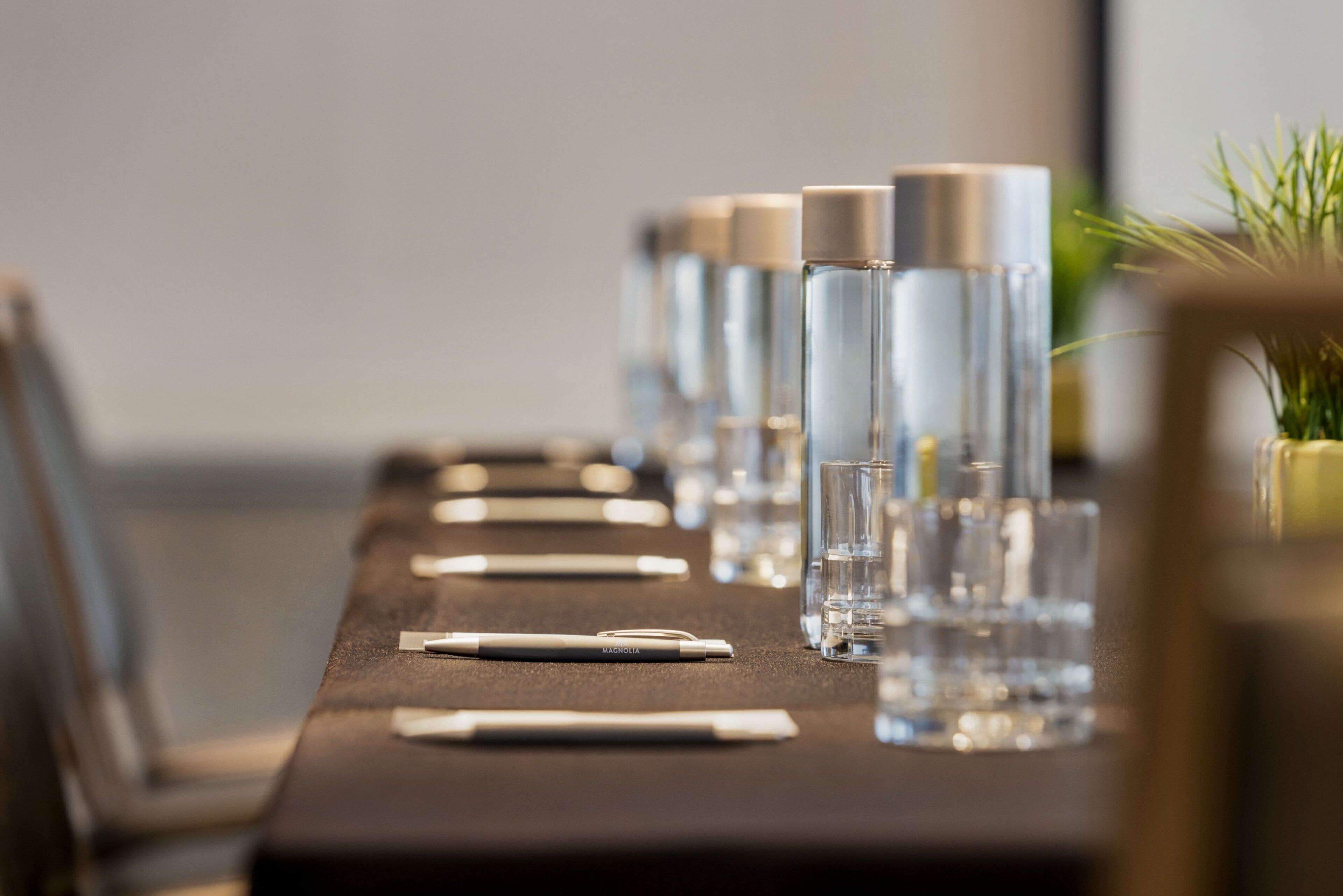 A conference table with water bottles, glasses, and pens.