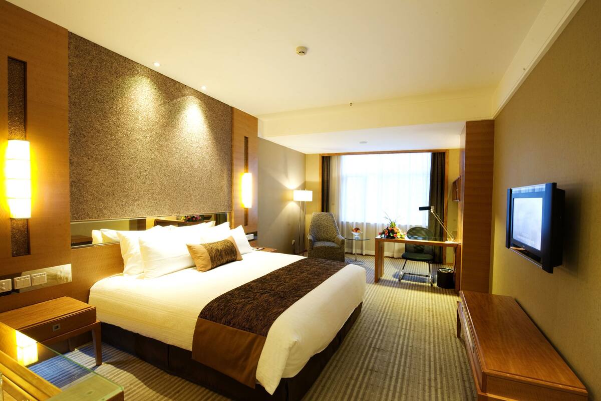 Habitación de hotel con una cama grande, un escritorio, una silla, un televisor y una ventana con vistas.