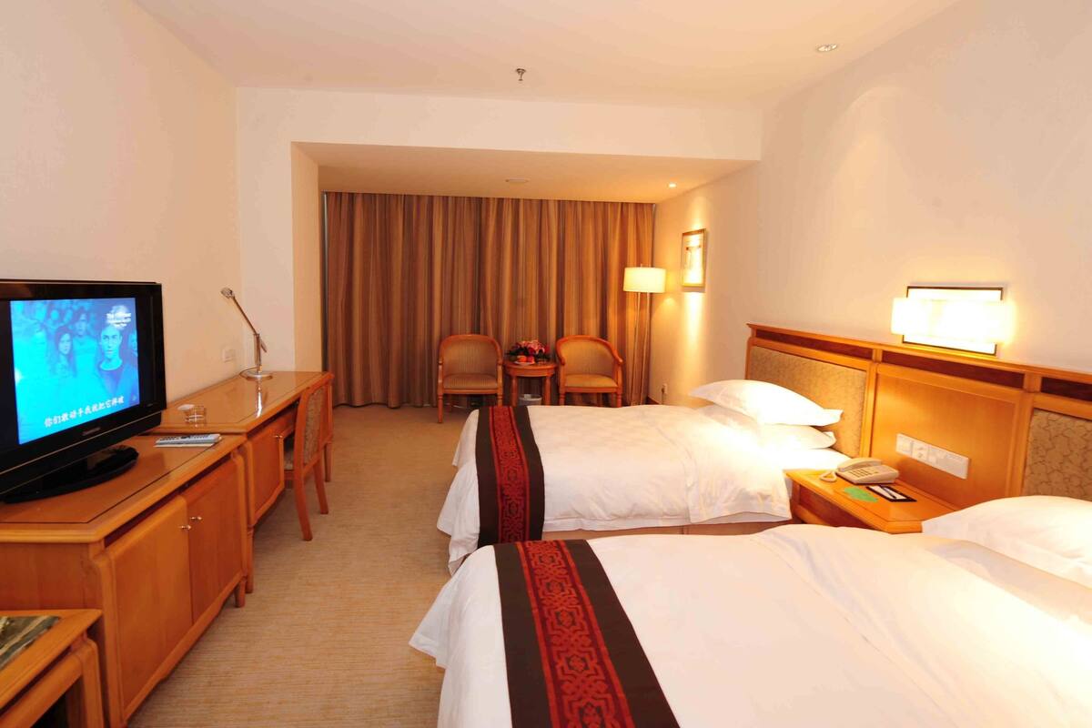 Una habitación de hotel con dos camas, televisión, escritorio y una silla.