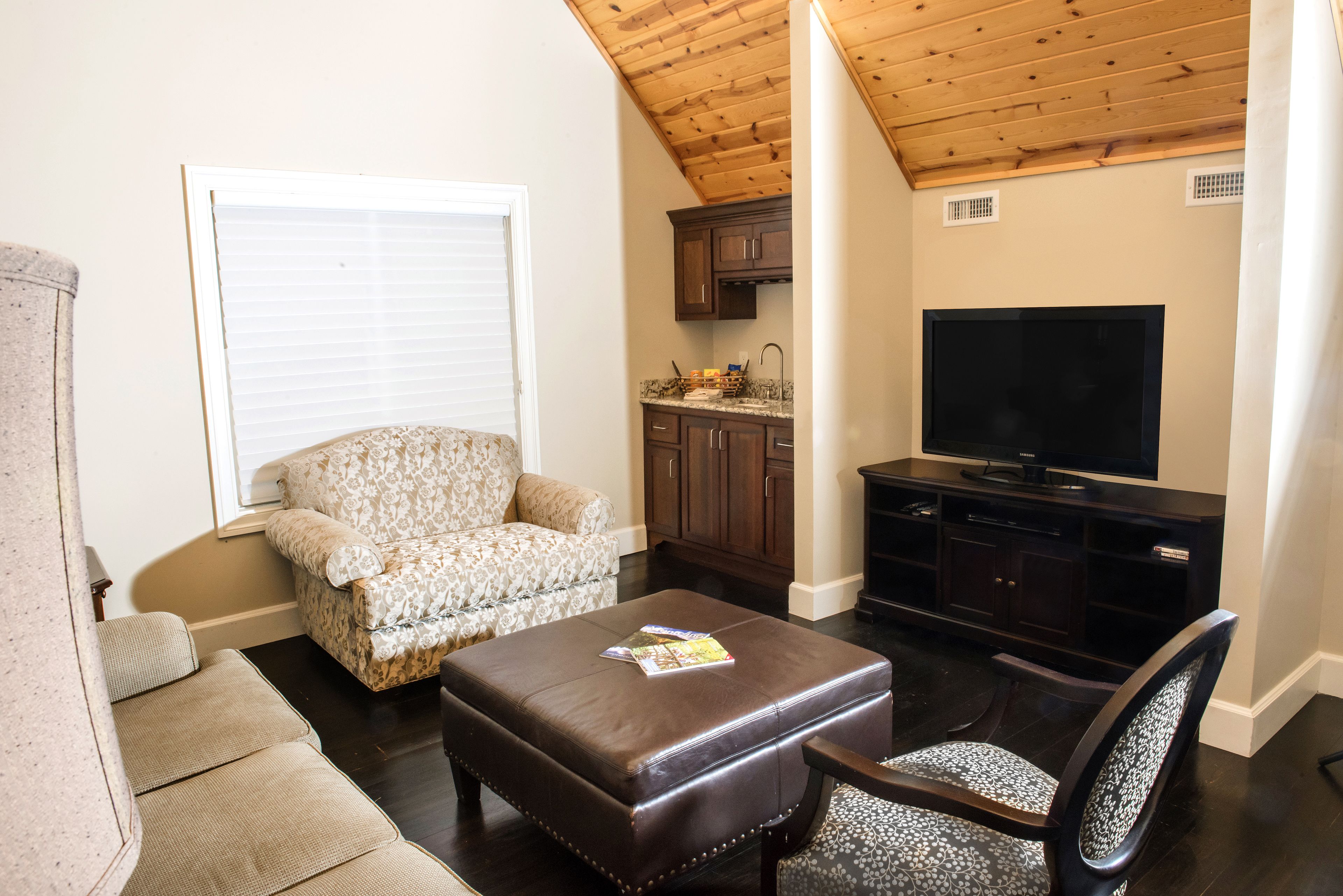 A living room with a sofa, ottoman, and a television.