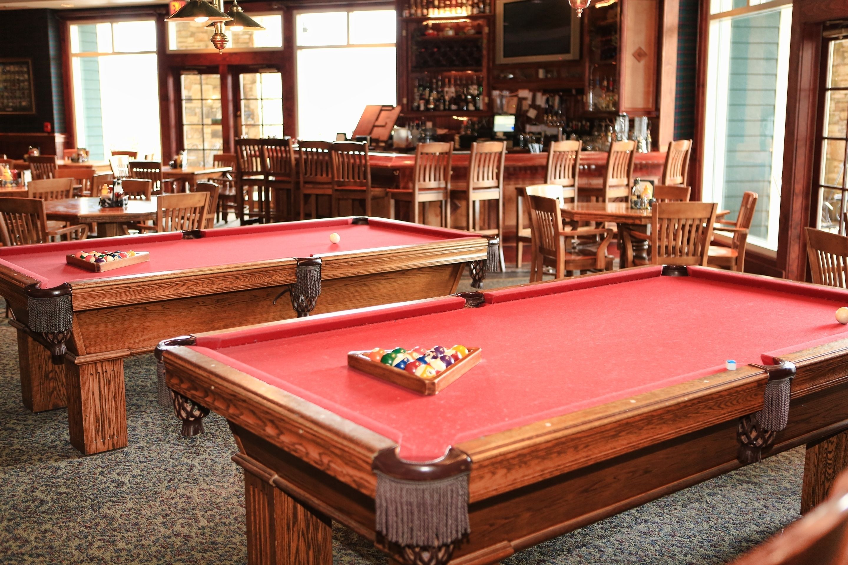 A pool table with a red felt surface and a set of pool balls in the center.