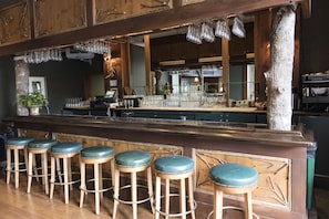 Eine Bar mit Holzhockern, einer Bar und hängenden Gläsern.