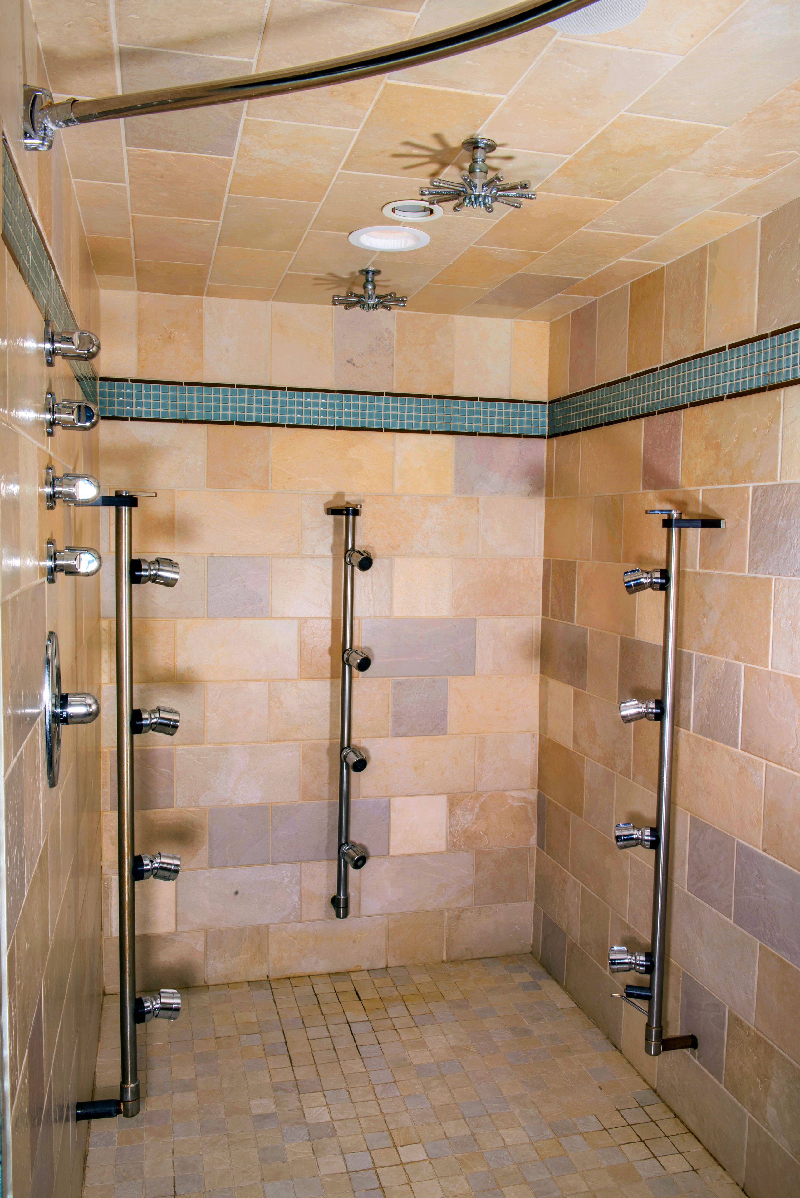 A walk-in shower with multiple showerheads and a ceiling-mounted light fixture.