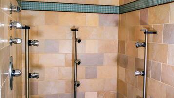 A walk-in shower with multiple showerheads and a ceiling-mounted light fixture.