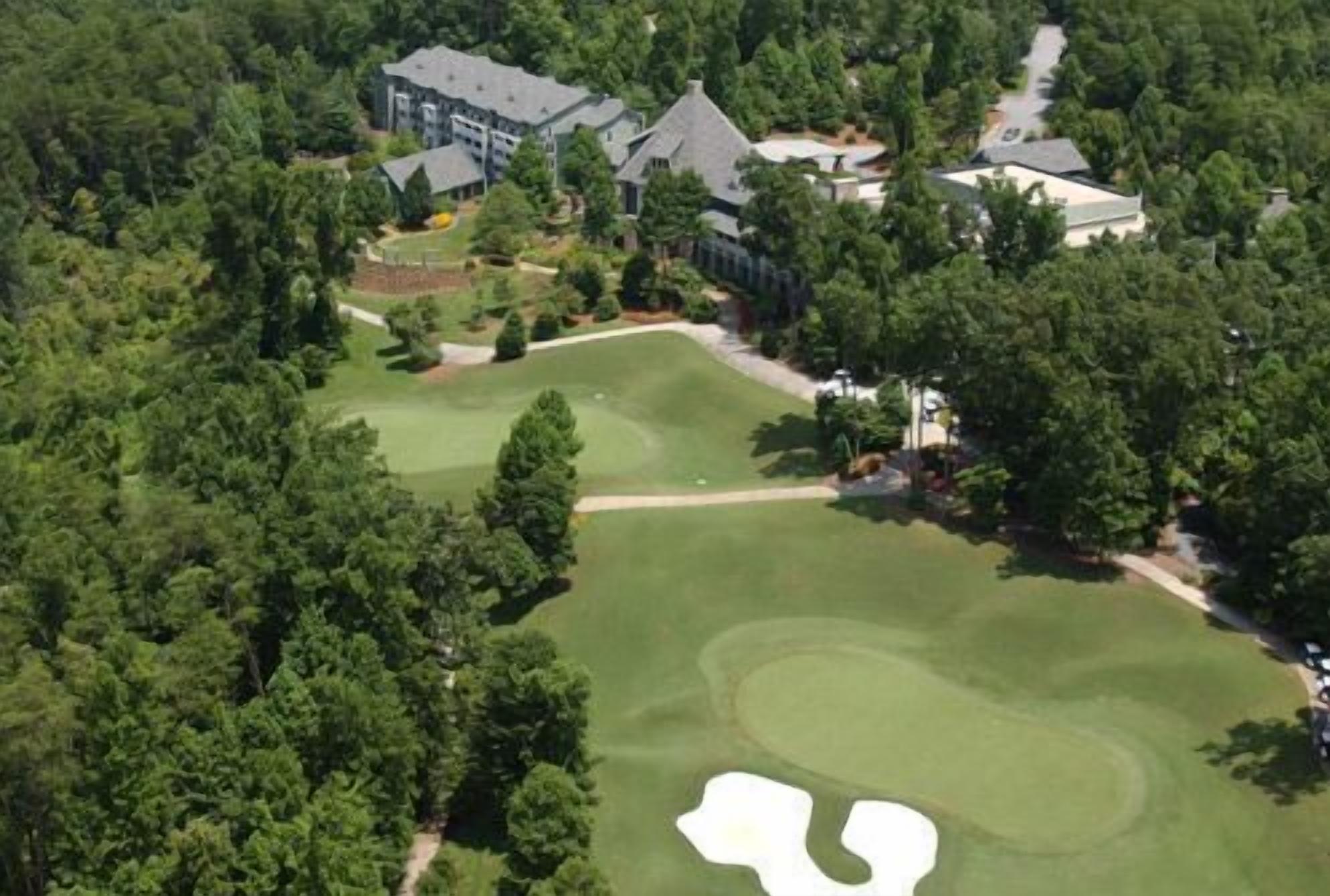 An aerial view of a golf course with a clubhouse and residential buildings.