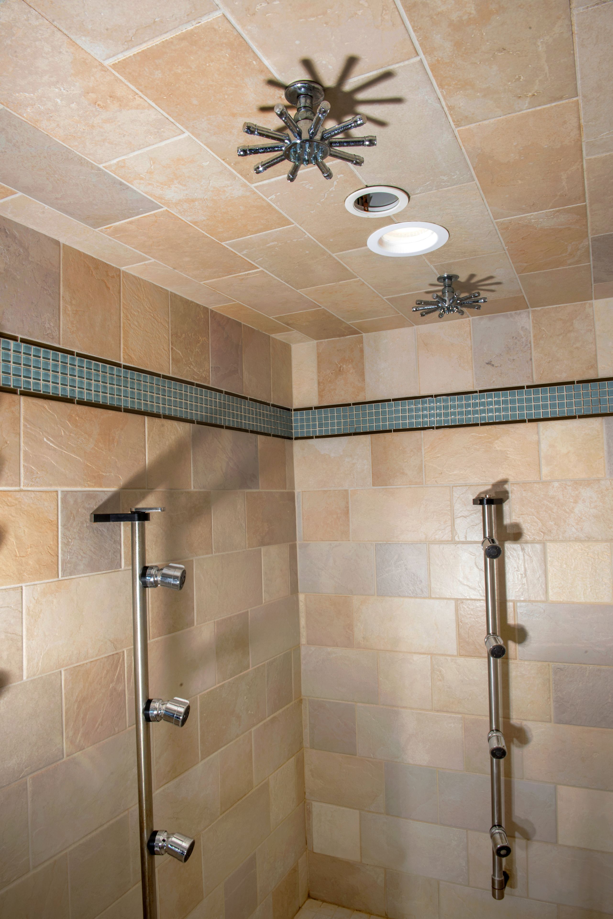 A shower with multiple faucets and a ceiling-mounted showerhead.