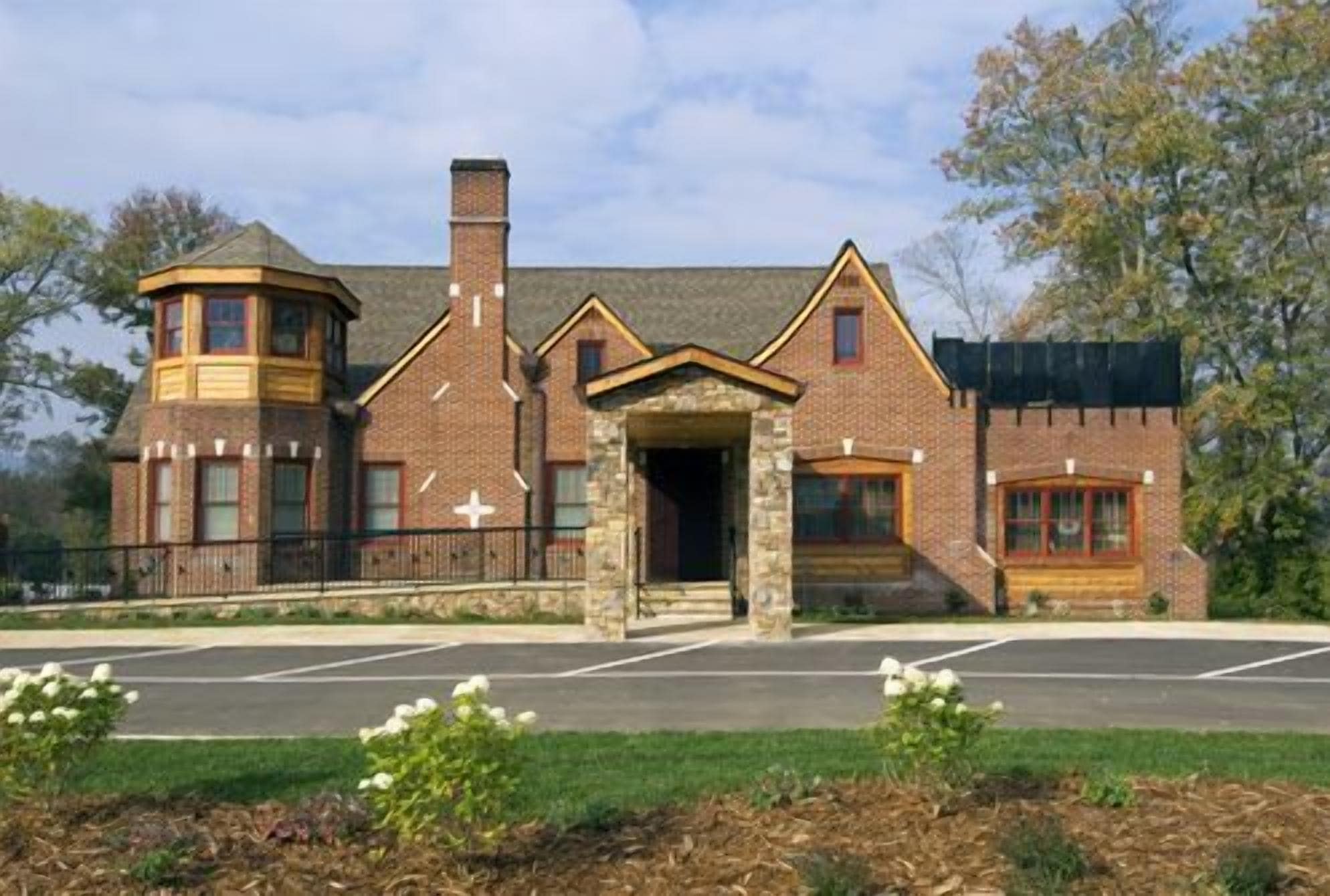 A brick building with a central entrance, a turret, and a covered porch area.