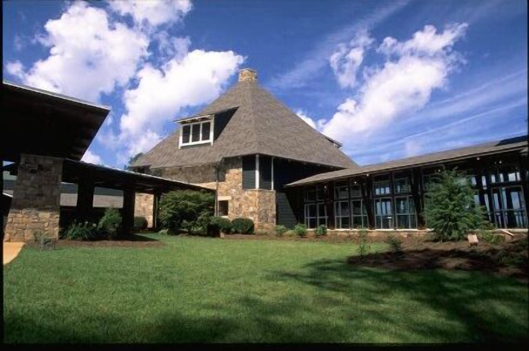 A house with a thatched roof, stone walls, and a covered porch.