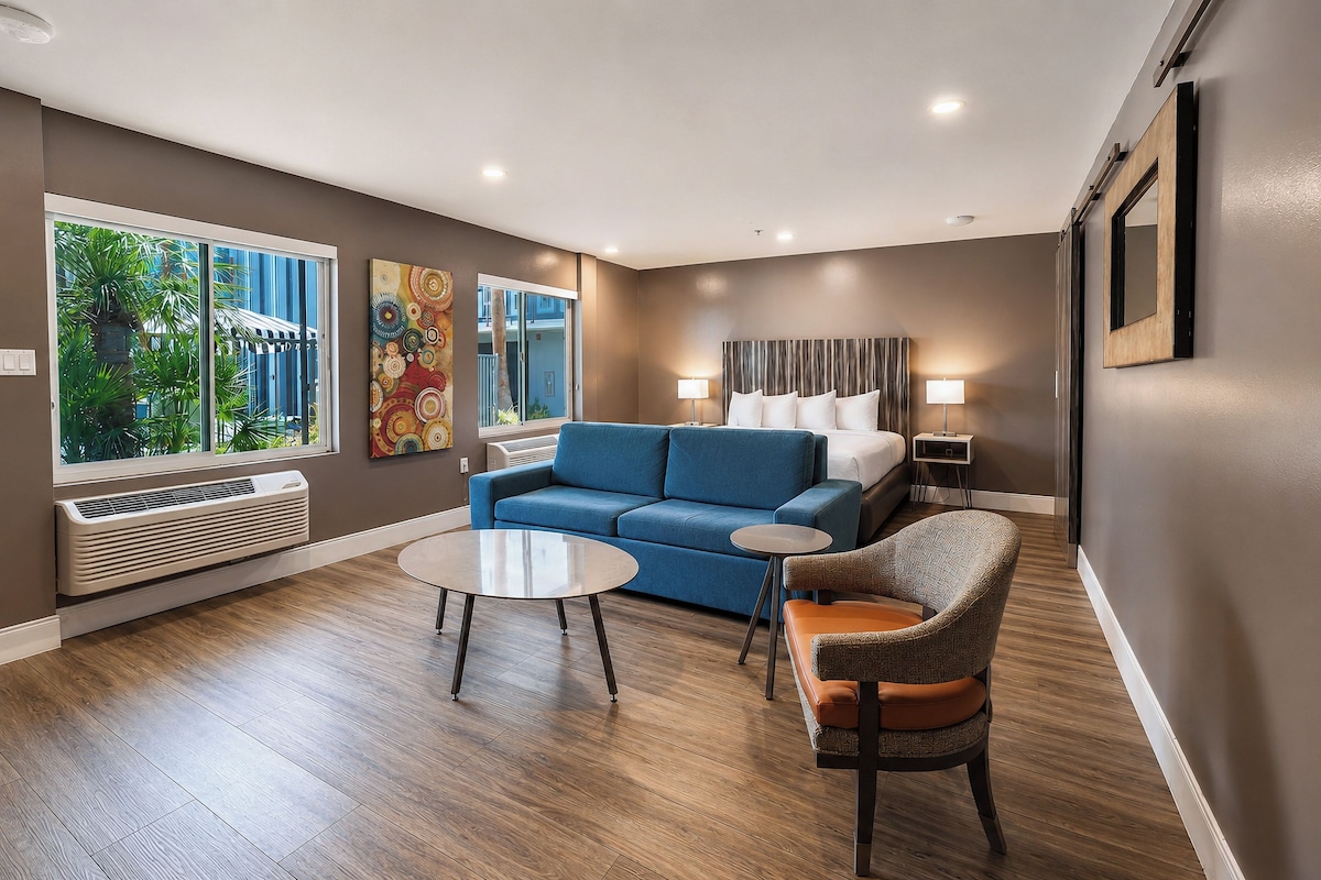 A modern hotel room with a blue sofa, a round table, and a chair.
