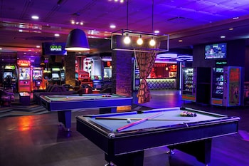 A pool table in a room with a wooden floor, a bar area with stools, and a seating area with a couch and chairs. at Oasis at Gold Spike