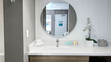 A bathroom with a round mirror, white sink, and a towel rack.