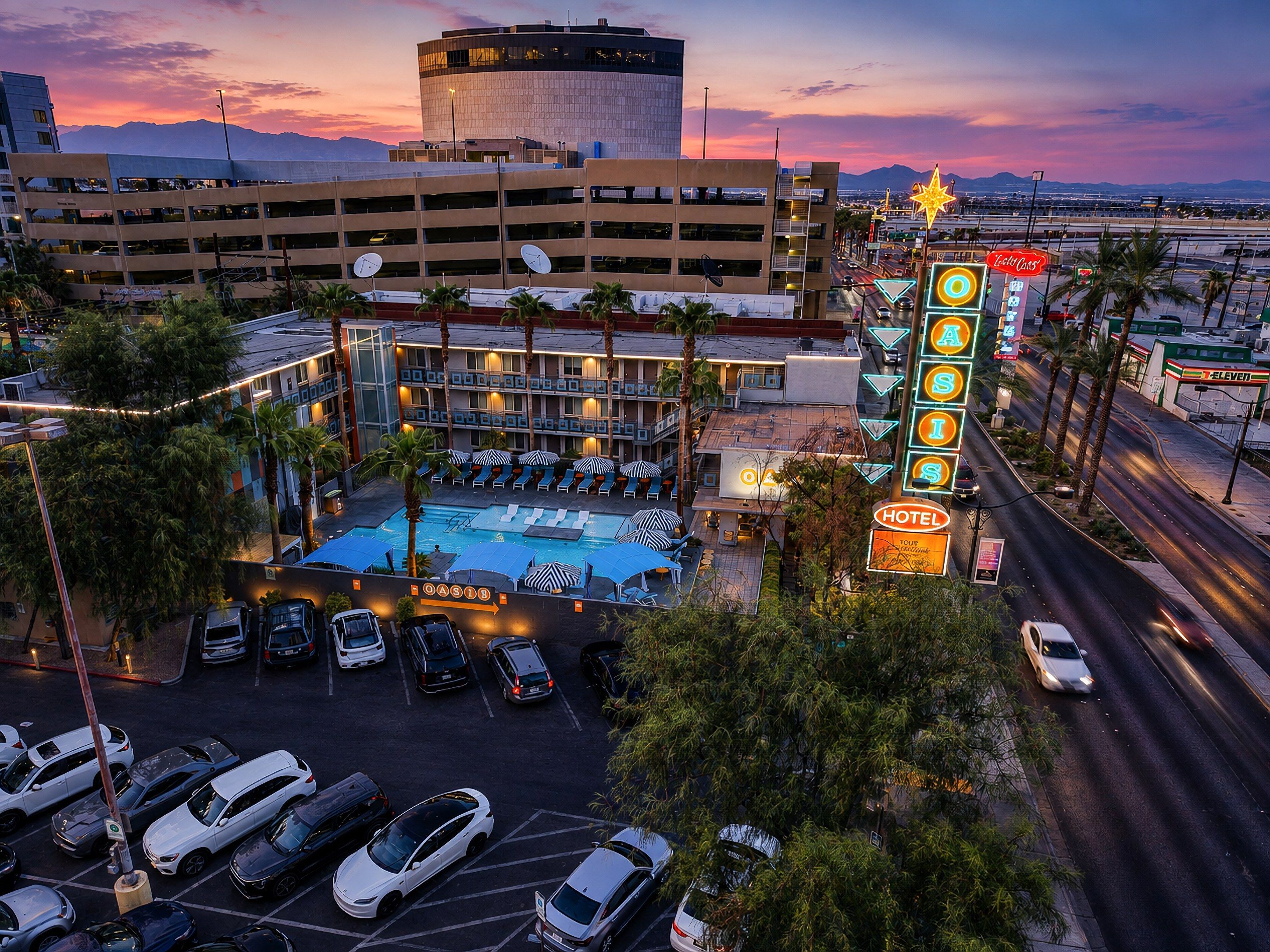 A hotel with a swimming pool, parking garage, and a neon sign.