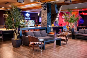 A modern lounge area with sofas, a pool table, and potted plants. - Oasis at Gold Spike (Las Vegas)