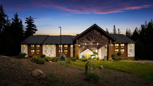 A large building with a prominent entrance, multiple windows, and a landscaped garden with rocks and shrubs. - Best Western Mt. Hood Inn (Government Camp)