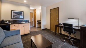 A modern hotel room with a kitchenette, a gray sofa, a wooden desk, and a black office chair. - Best Western Mt. Hood Inn (Government Camp)
