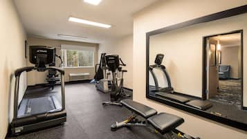 A gym with treadmills, elliptical machines, and a bench.