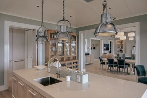A modern kitchen with a central island, pendant lighting, and a dining area with a round table and chairs.