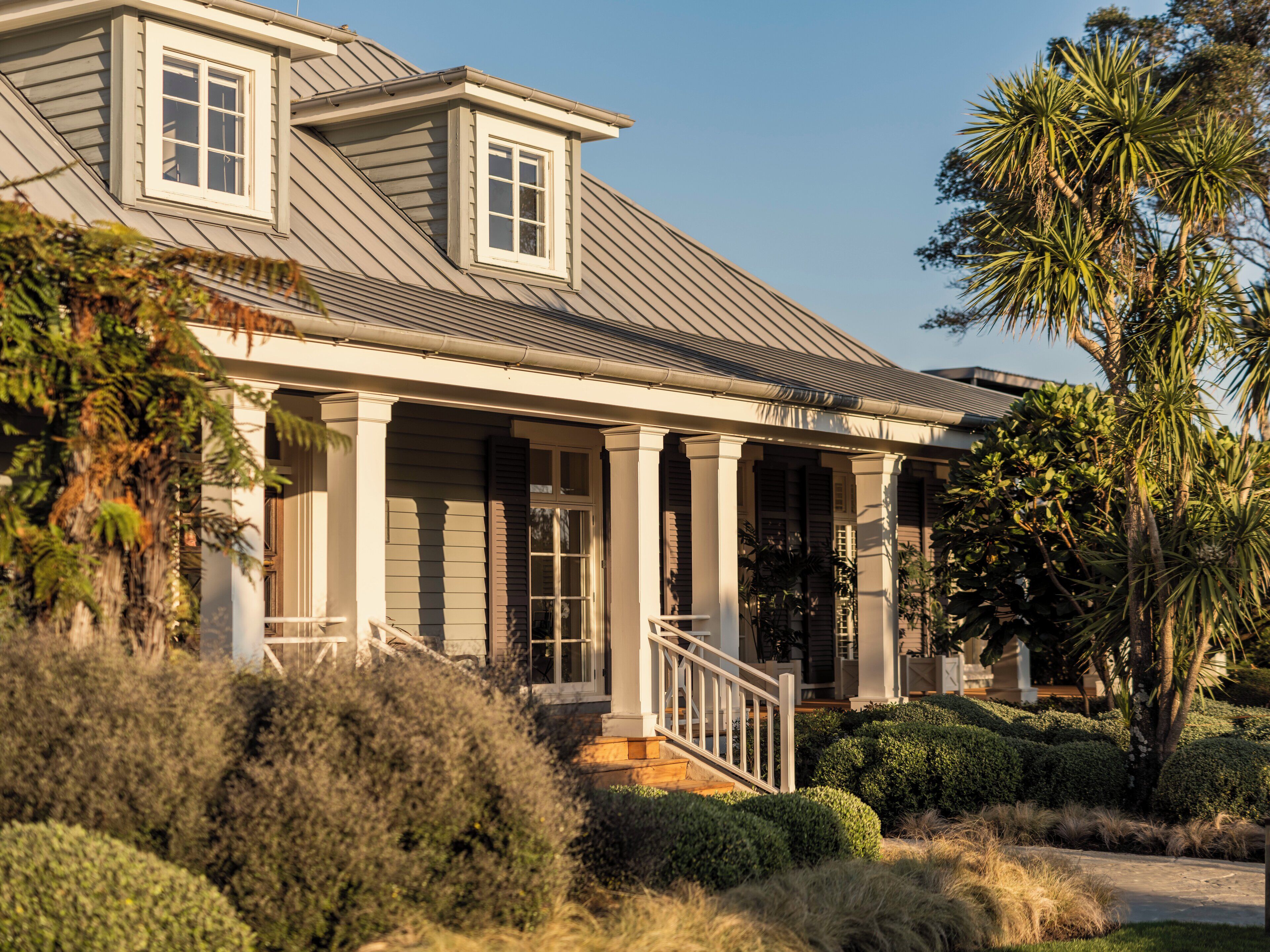A two-story house with a covered porch, columns, and a small window on the upper floor.
