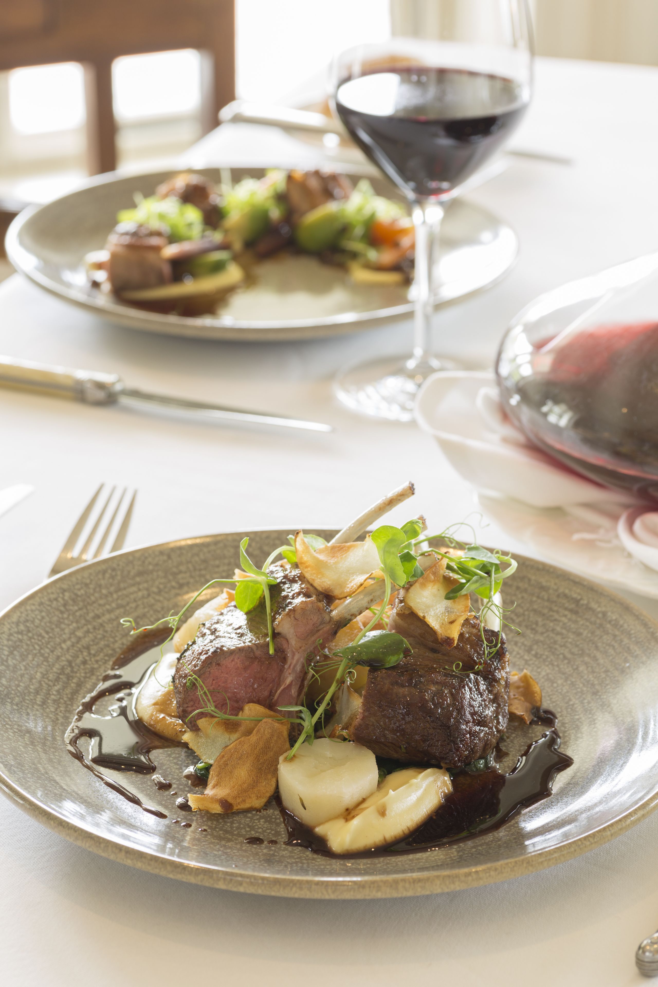 Ein Teller mit Essen und ein Glas Rotwein auf einem Tisch.