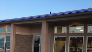 A building with a stone facade, large windows, and a blue-lit roof. - Bay Hill Inns & Suites, Neepawa (Neepawa)
