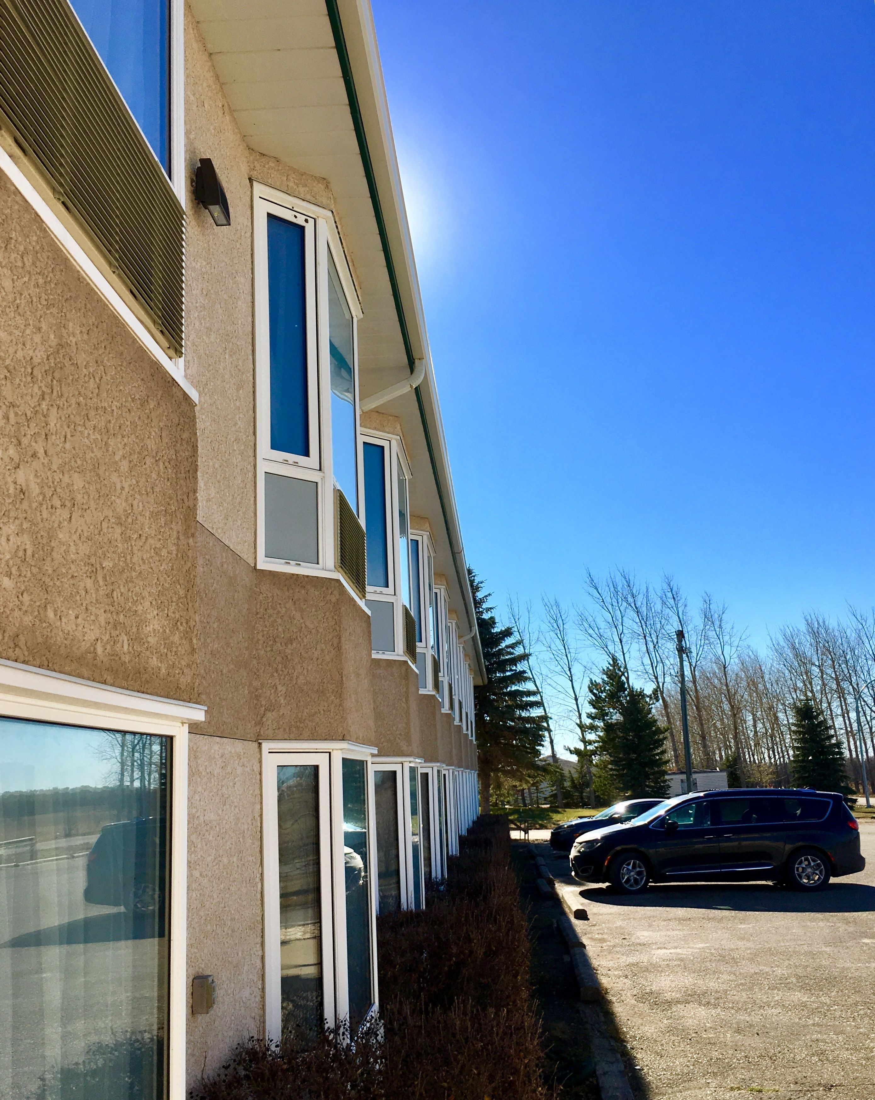 A multi-story building with large windows and a parking lot.