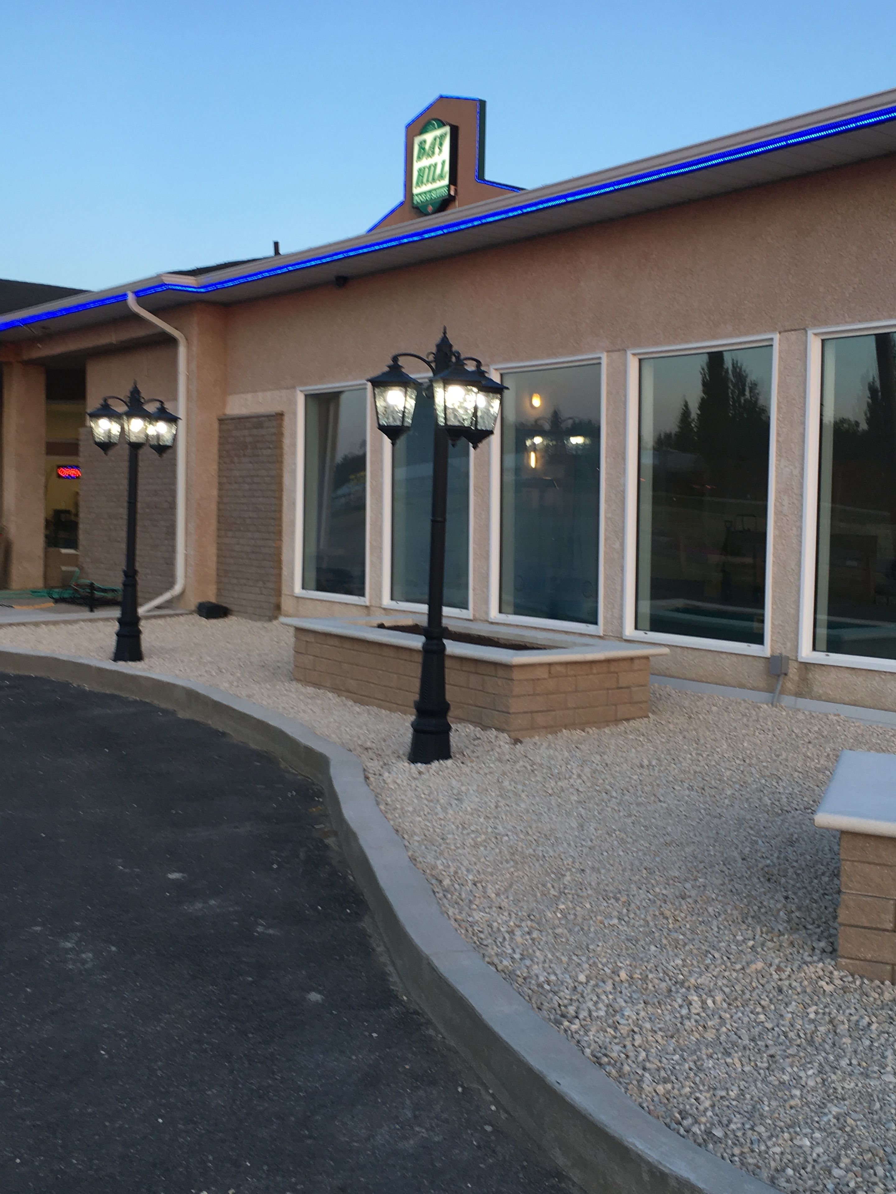 A building with a 'Bay Hill Inn' sign, large windows, and two black street lamps.