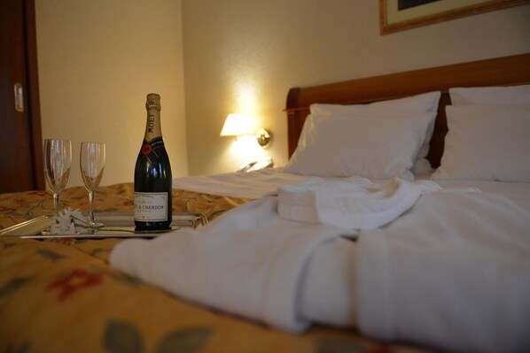 Una habitación de hotel con una cama, una botella de champán y dos copas sobre una bandeja.