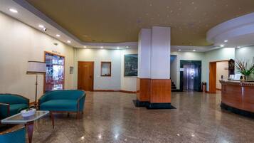 A lobby with a reception desk, a snack bar, and a seating area with chairs and a table.