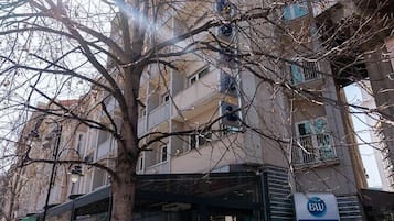 Un bâtiment portant l’enseigne d’un hôtel Best Western, avec un arbre devant et un banc.
