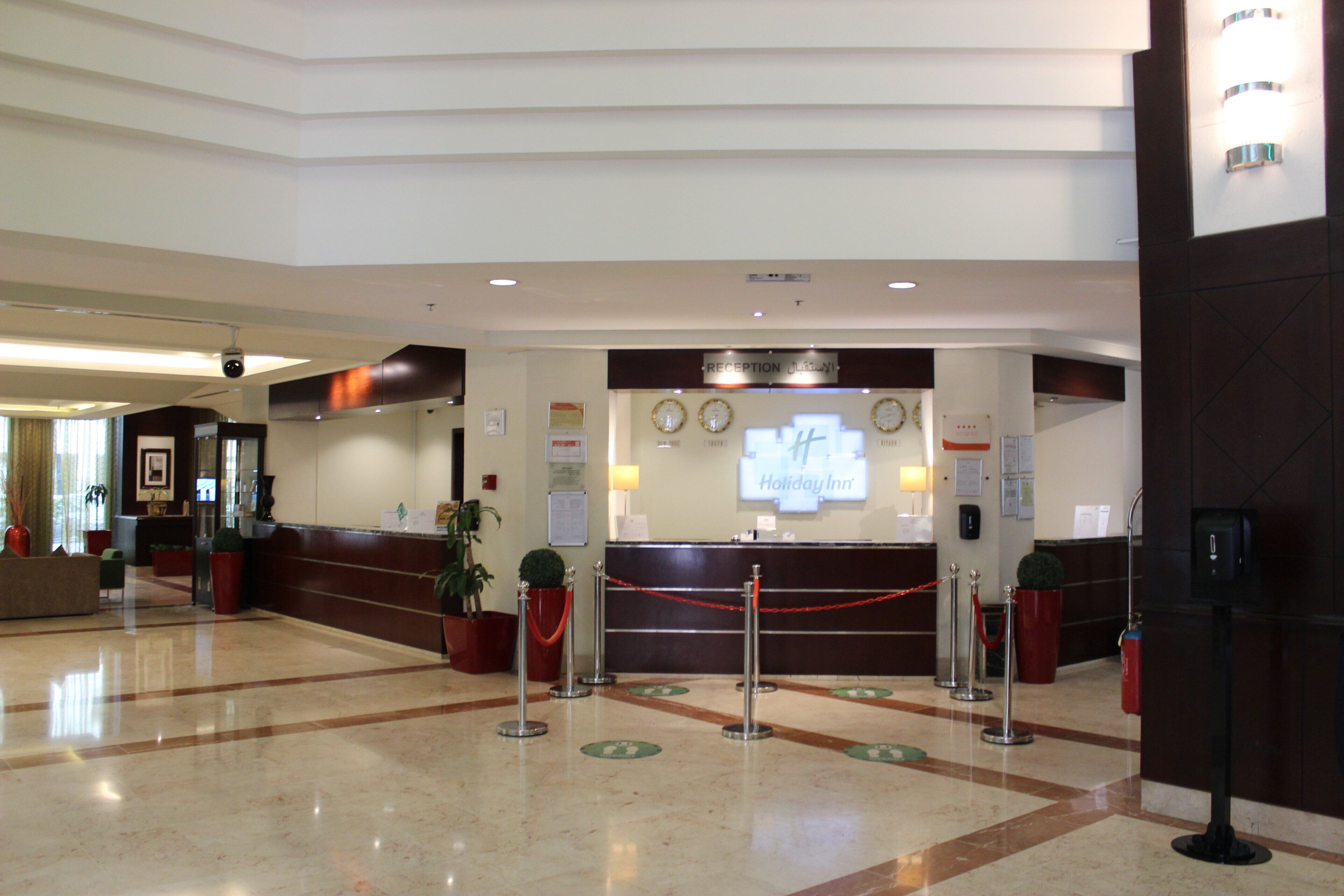 Un espace d’accueil d’hôtel comprenant un comptoir de réception, une horloge et un panneau indiquant « Holiday Inn ».