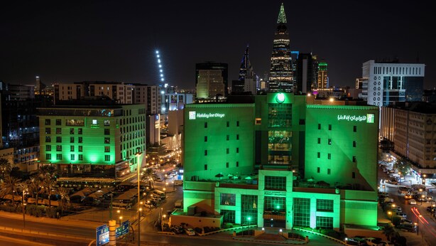 A large hotel with a prominent green facade, multiple floors, and a central tower. - Holiday Inn Riyadh-Olaya by IHG (Riyadh)