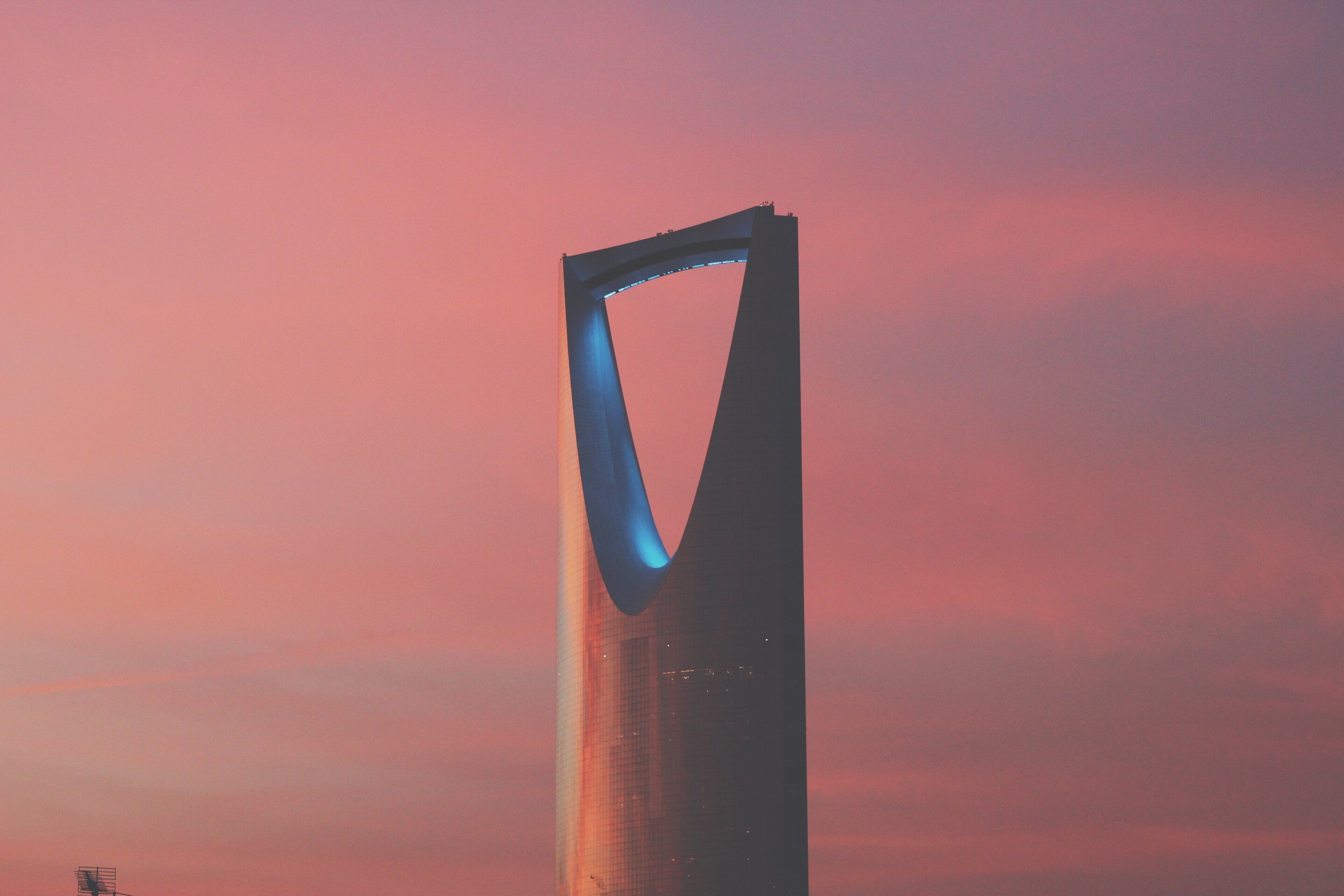 A tall, modern building with a unique architectural design, featuring a prominent arch structure.
