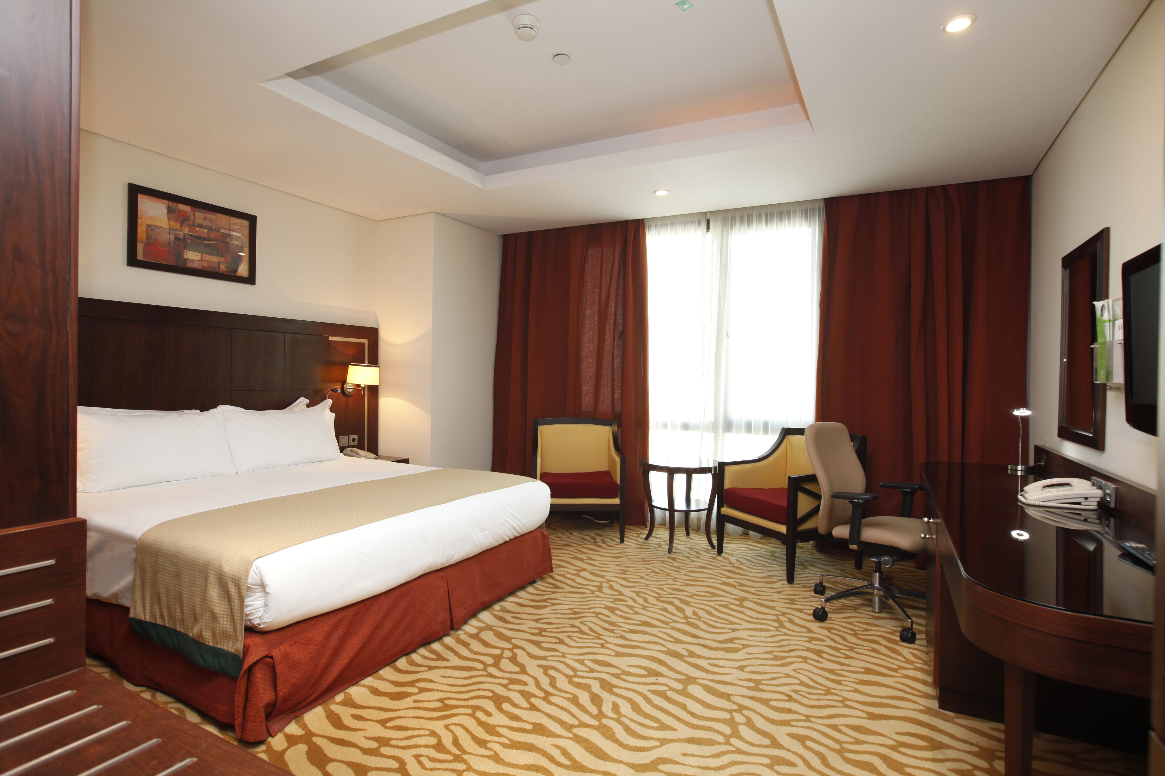 Une chambre d’hôtel avec un grand lit, un bureau avec une chaise, une petite table et un téléviseur.