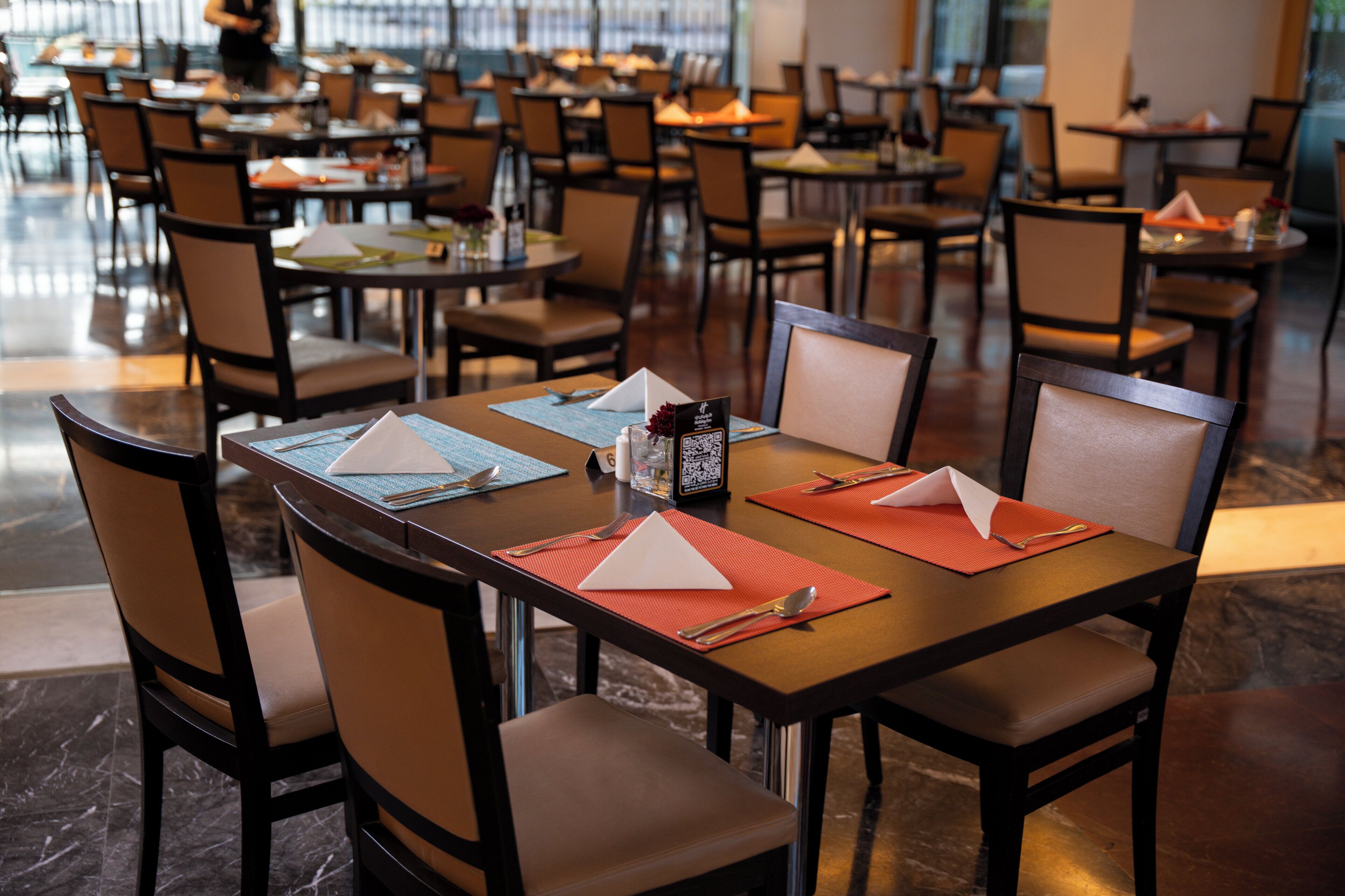 Un restaurante con numerosas mesas y sillas, dispuesto en un espacio amplio.