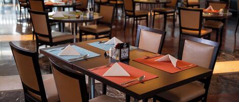 Un restaurante con numerosas mesas y sillas, dispuesto en un espacio amplio.