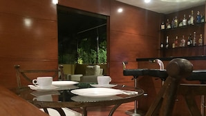 Comedor con una mesa redonda, sillas y una barra con estantes llenos de botellas.